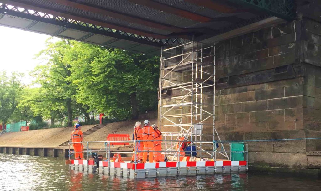 FPS modular pontoon working platform with edge protection and a scaffold tower beneath a bridge, providing close-range inspection access